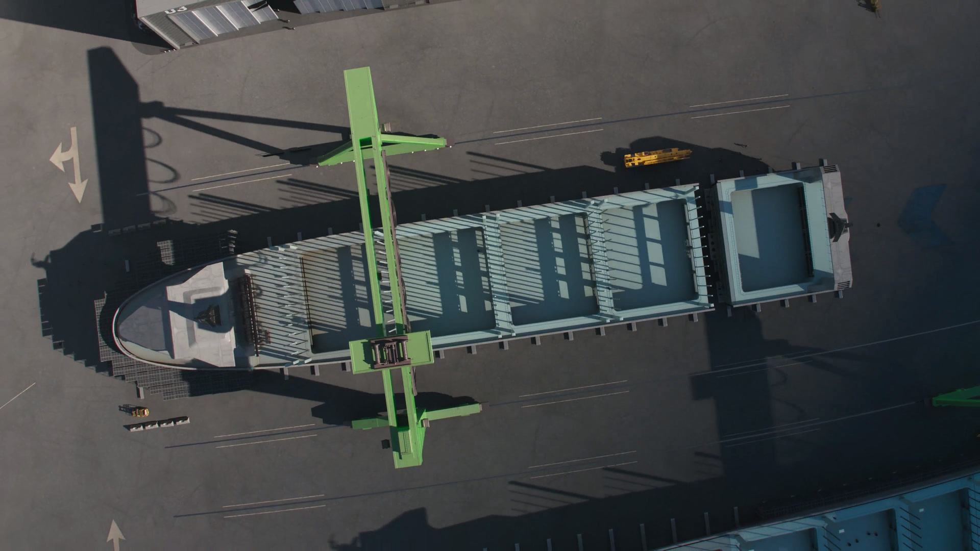 Overhead rendering of a vessel in a Port Alpha build position beneath a gantry crane